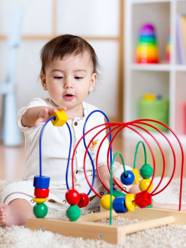 baby girl playing with educational toy in nursery