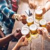 Group of people enjoying and toasting a beer in brewery pub - Friendship concept with young people having fun together