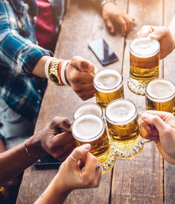 Group of people enjoying and toasting a beer in brewery pub - Friendship concept with young people having fun together
