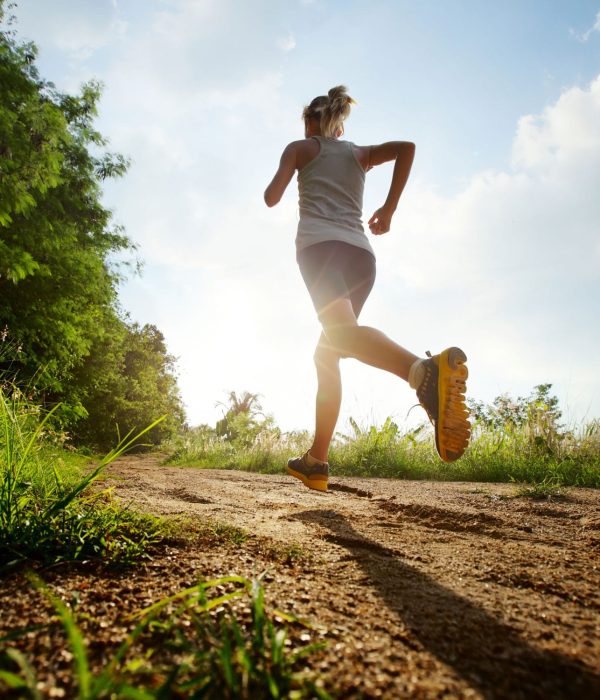 Young lady running on a rural road during sunset